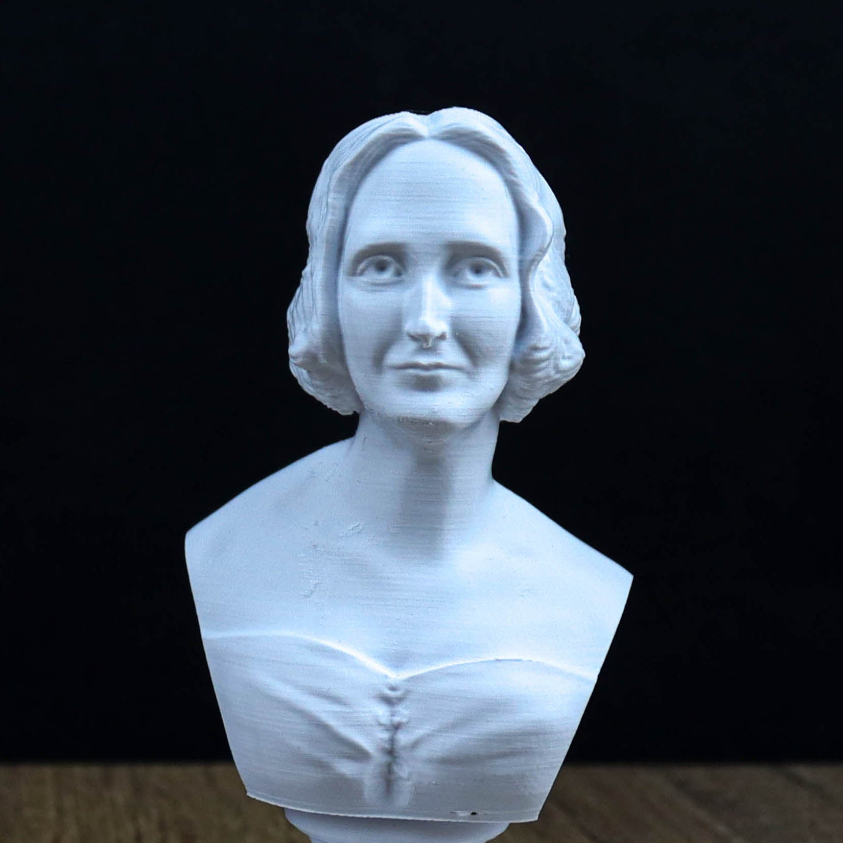 A white bust sculpture of a woman with a pensive expression, set against a dark background.