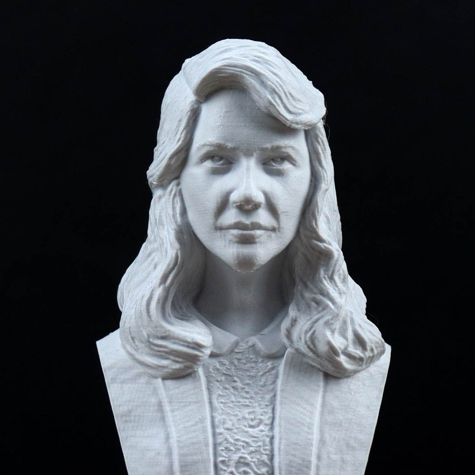 A white bust sculpture of a woman with long, wavy hair and a serious expression.