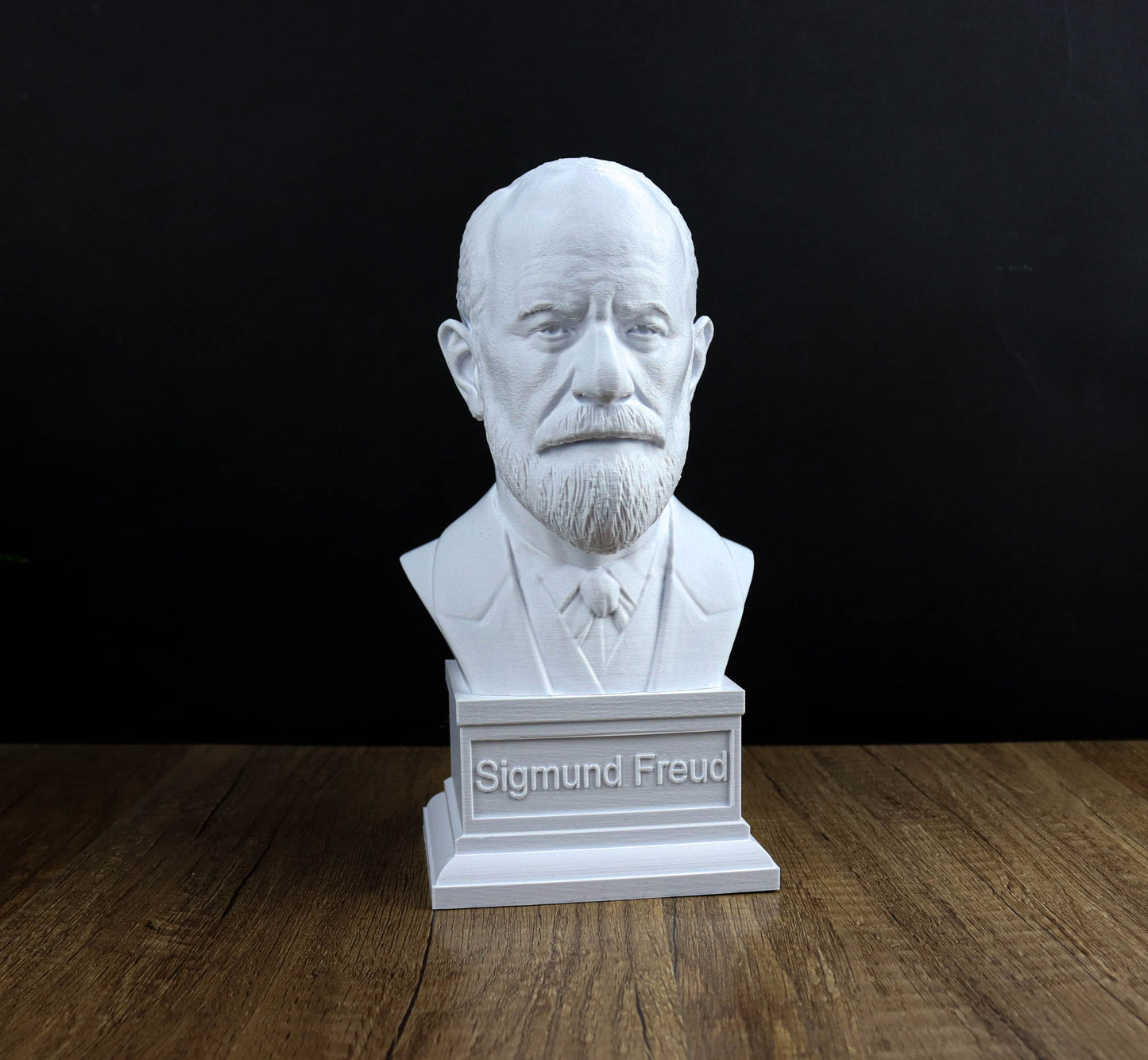 A white bust of a man with a beard and mustache, possibly a famous historical figure, displayed on a wooden surface.