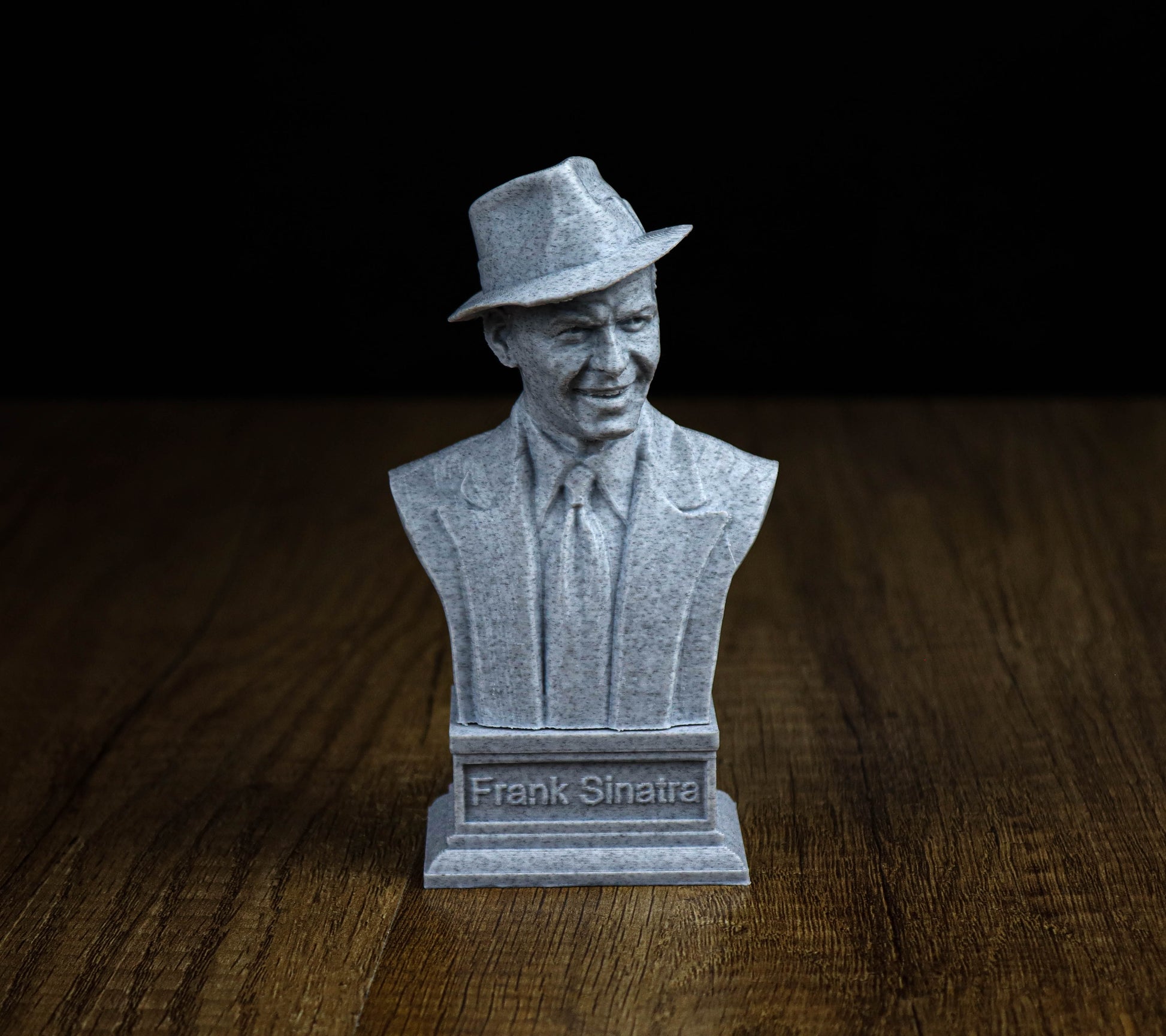 A bust of Frank Sinatra, a famous American singer, is displayed on a wooden surface.