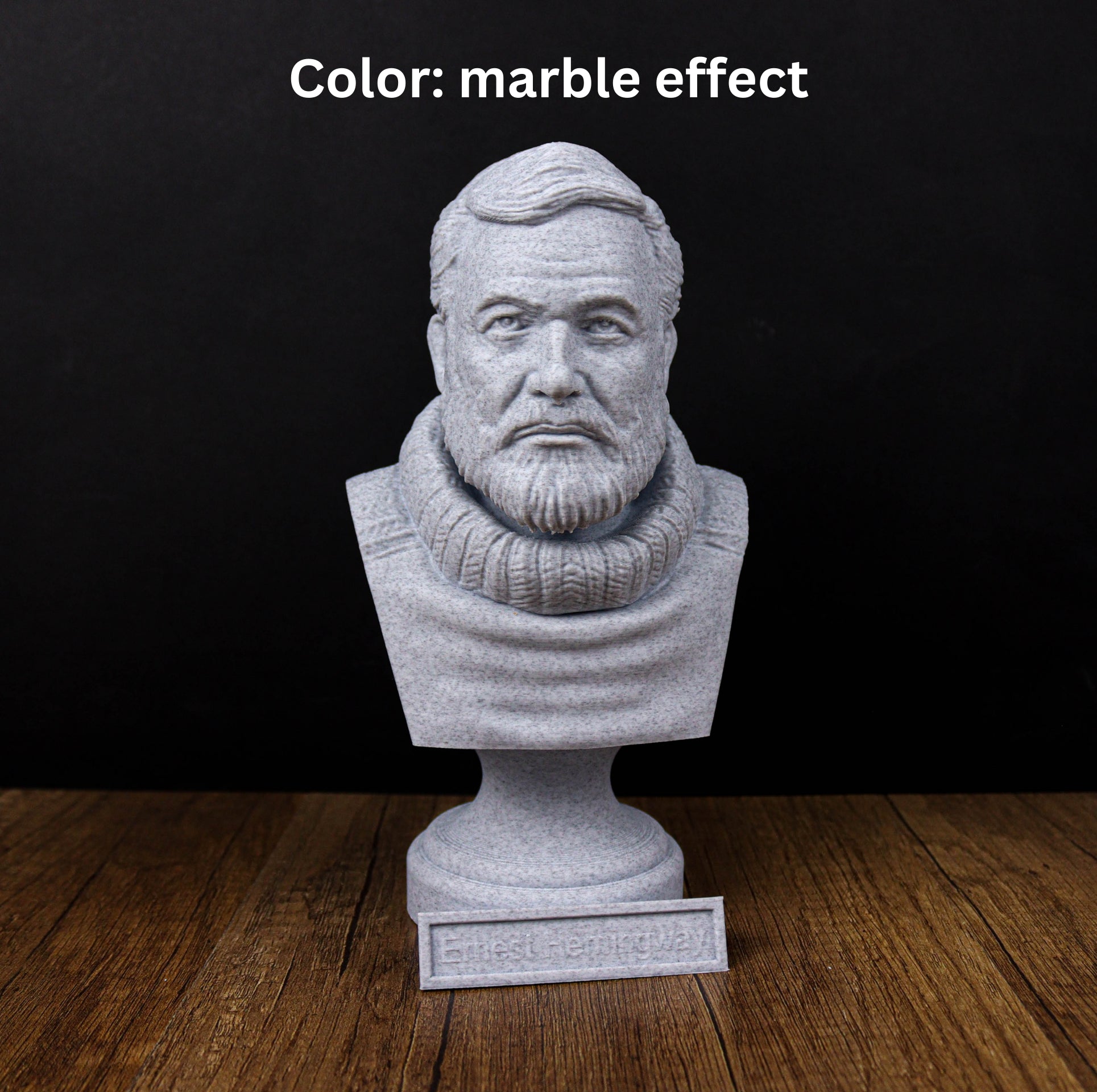 A gray stone bust of a man with a beard, placed on a wooden surface against a black background.