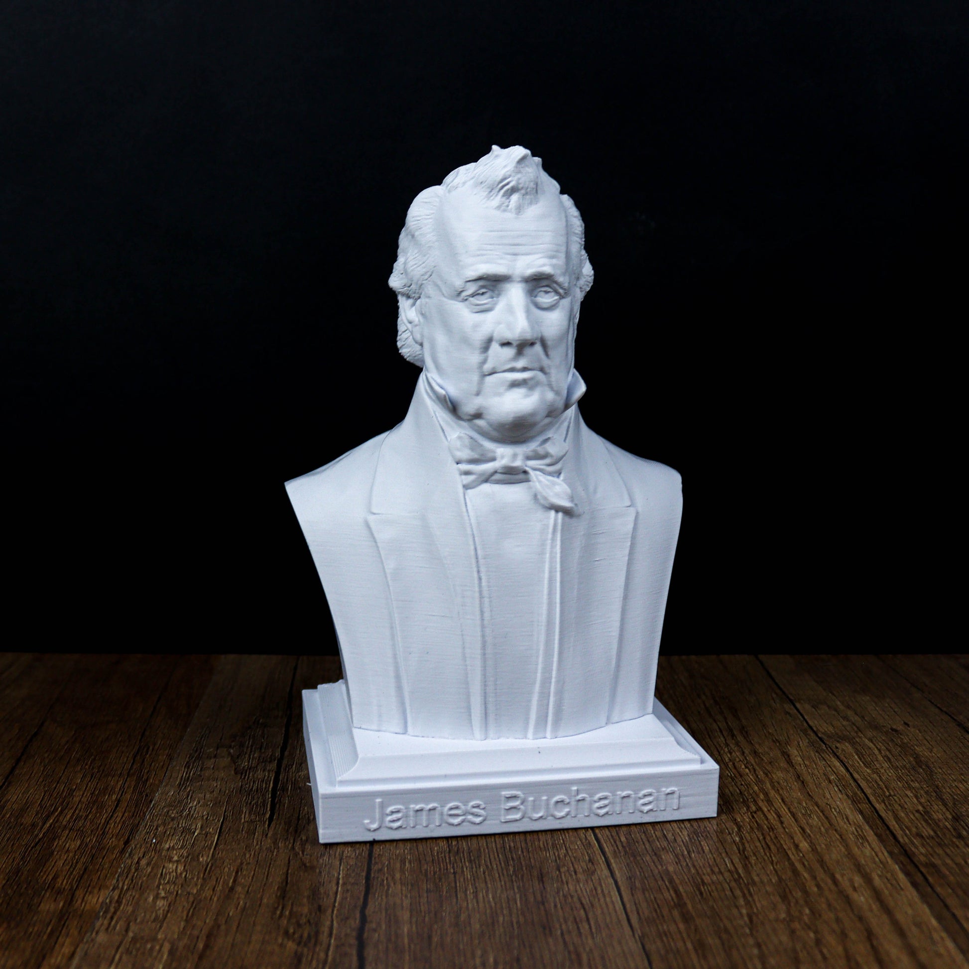 A white bust of a man, likely James Buchanan, is displayed on a wooden surface against a black background.