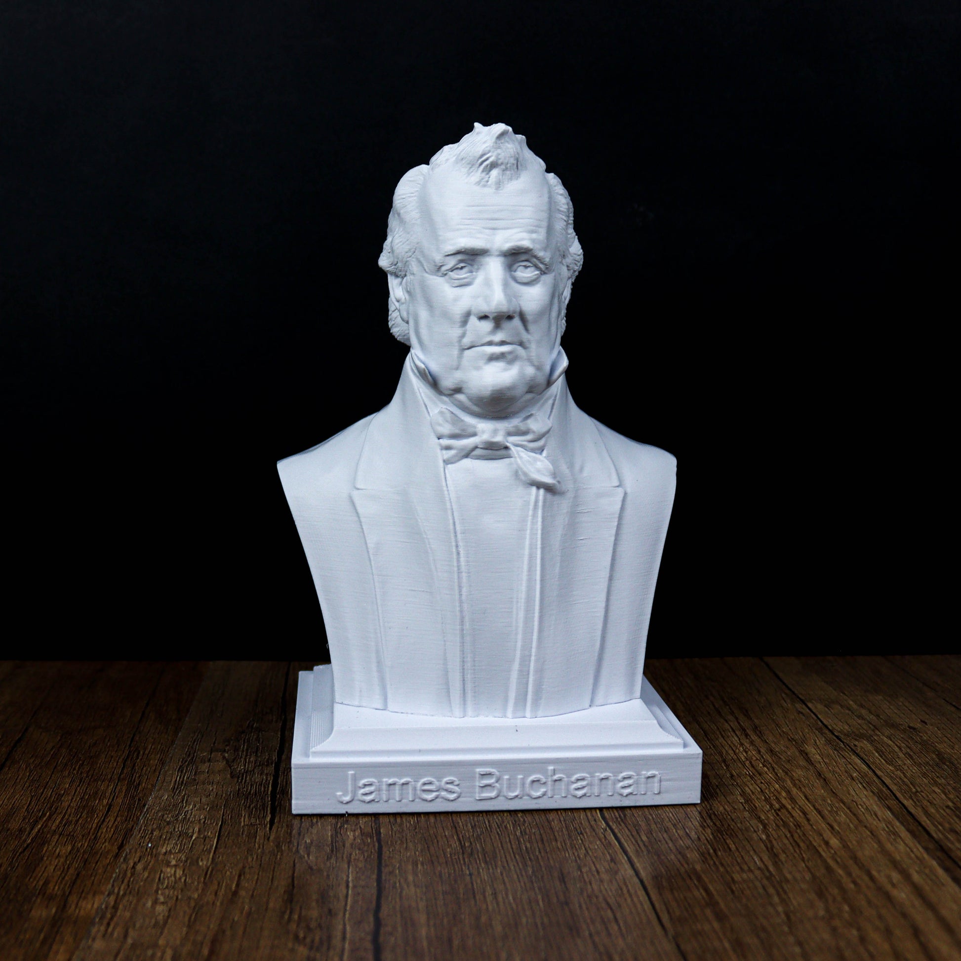 A white bust of a man with a serious expression, sitting on a wooden surface.