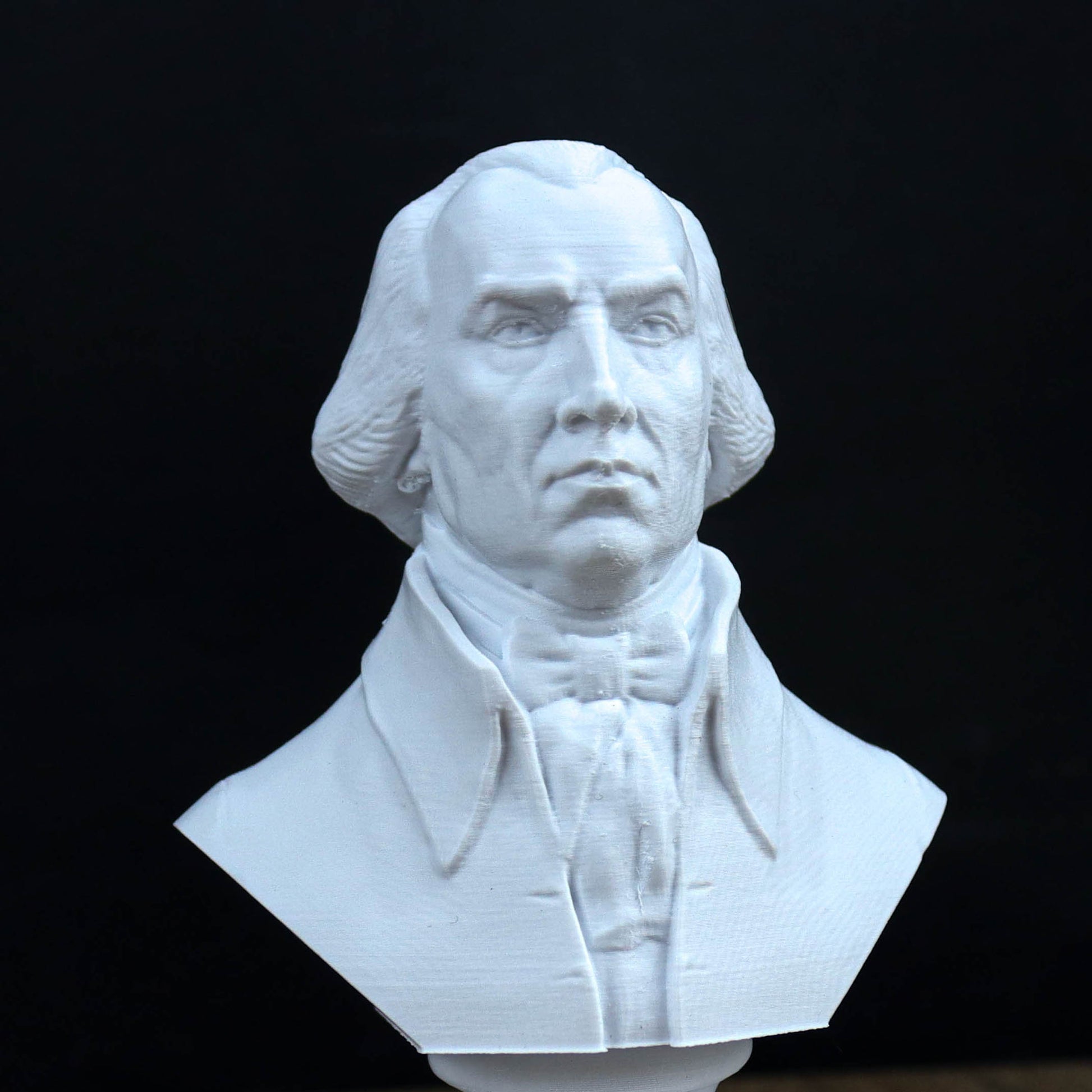 A white bust sculpture of a man with a serious expression, wearing a formal outfit.