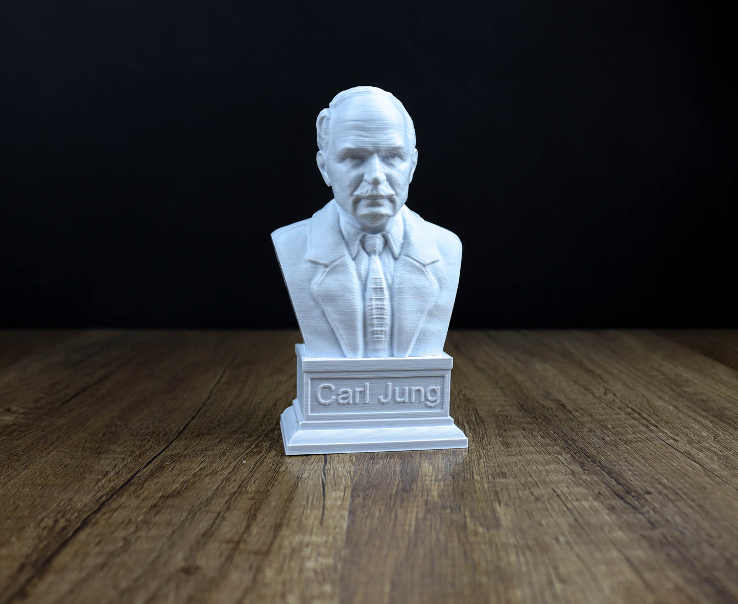 A white bust of a man wearing a suit and tie, with the name "Carl Jung" engraved on a pedestal below it.