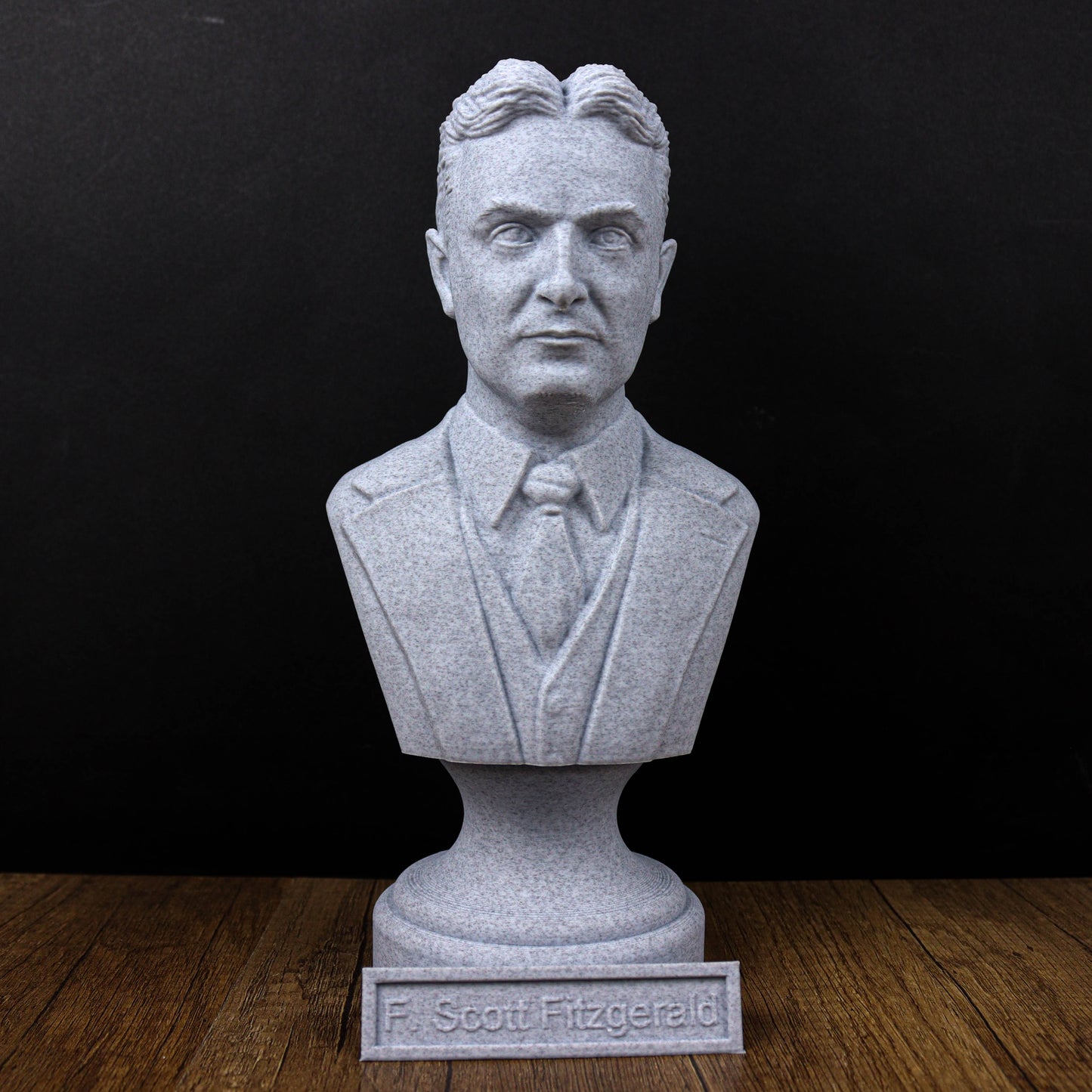 A bust of a man wearing a suit and tie, with the name "F. Scott Fitzgerald" displayed below the statue.