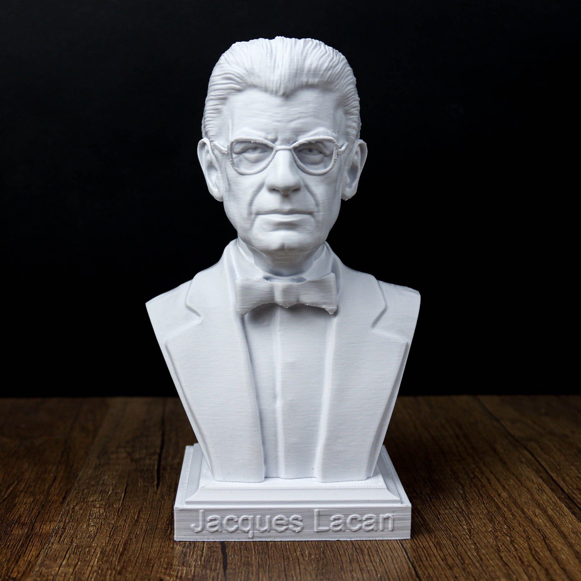A white bust of a man wearing a suit and bow tie, with the name "Jacques Lacan" written on the base.