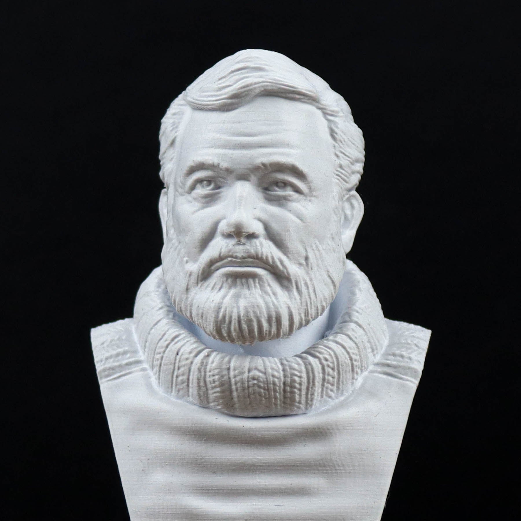 A white bust sculpture of a man with a beard and mustache, wearing a sweater.