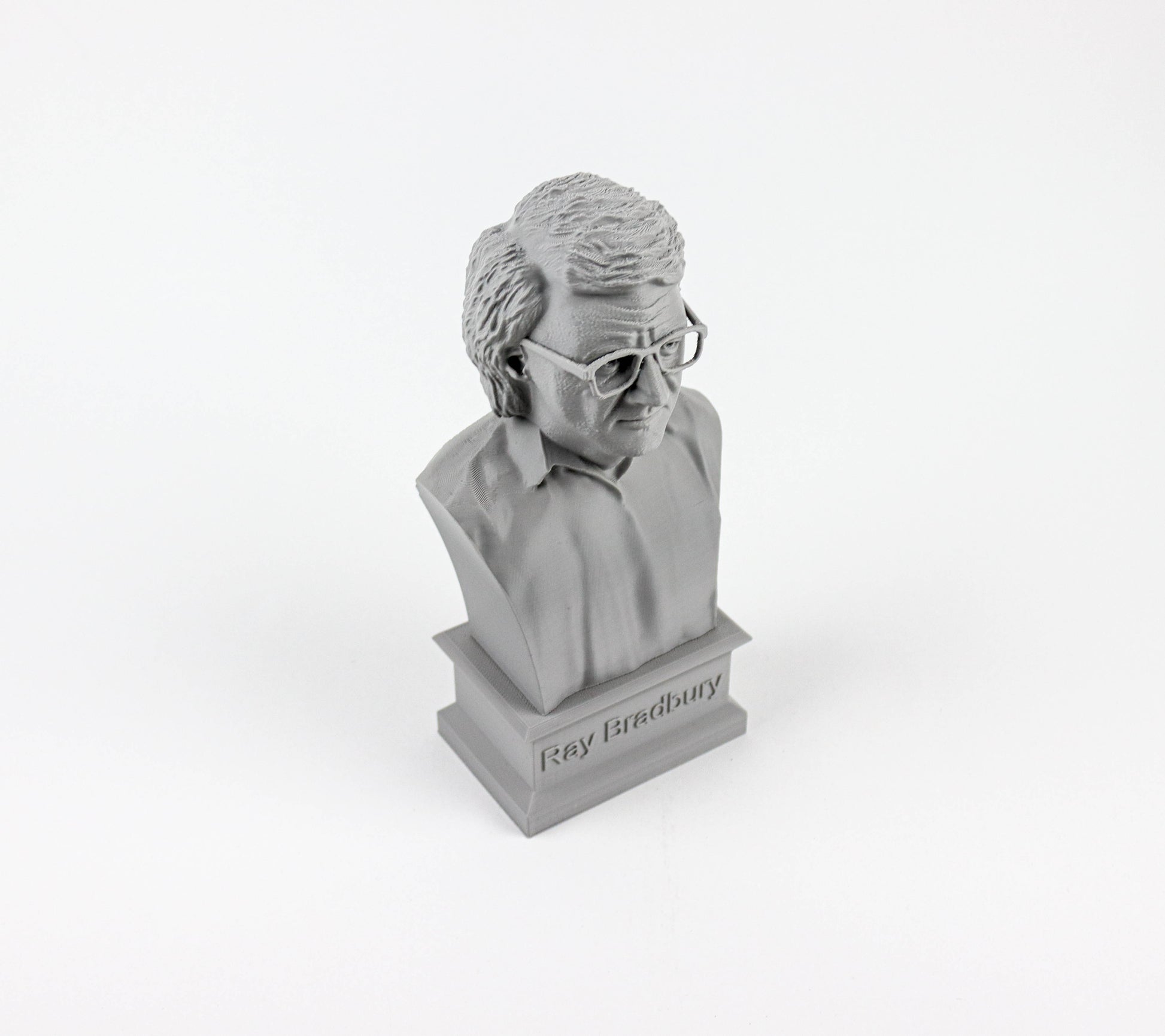 A small bust of a person wearing glasses, likely a famous individual, is displayed on a pedestal with the name "Ray Bradbury" inscribed below it.