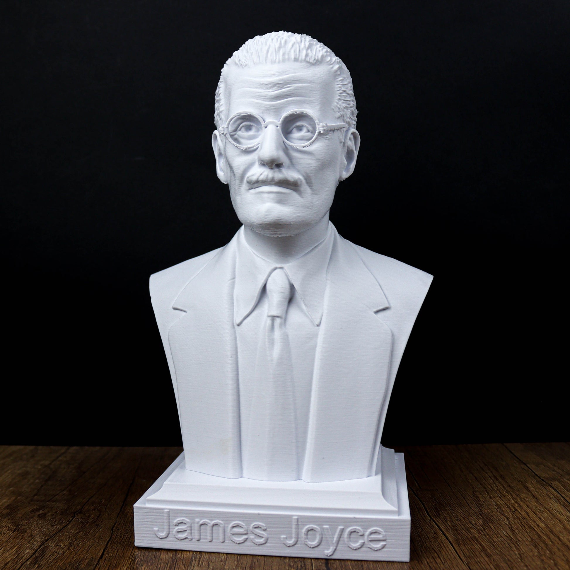 A white bust of a man wearing glasses and a suit, with the name "James Joyce" engraved on the base.