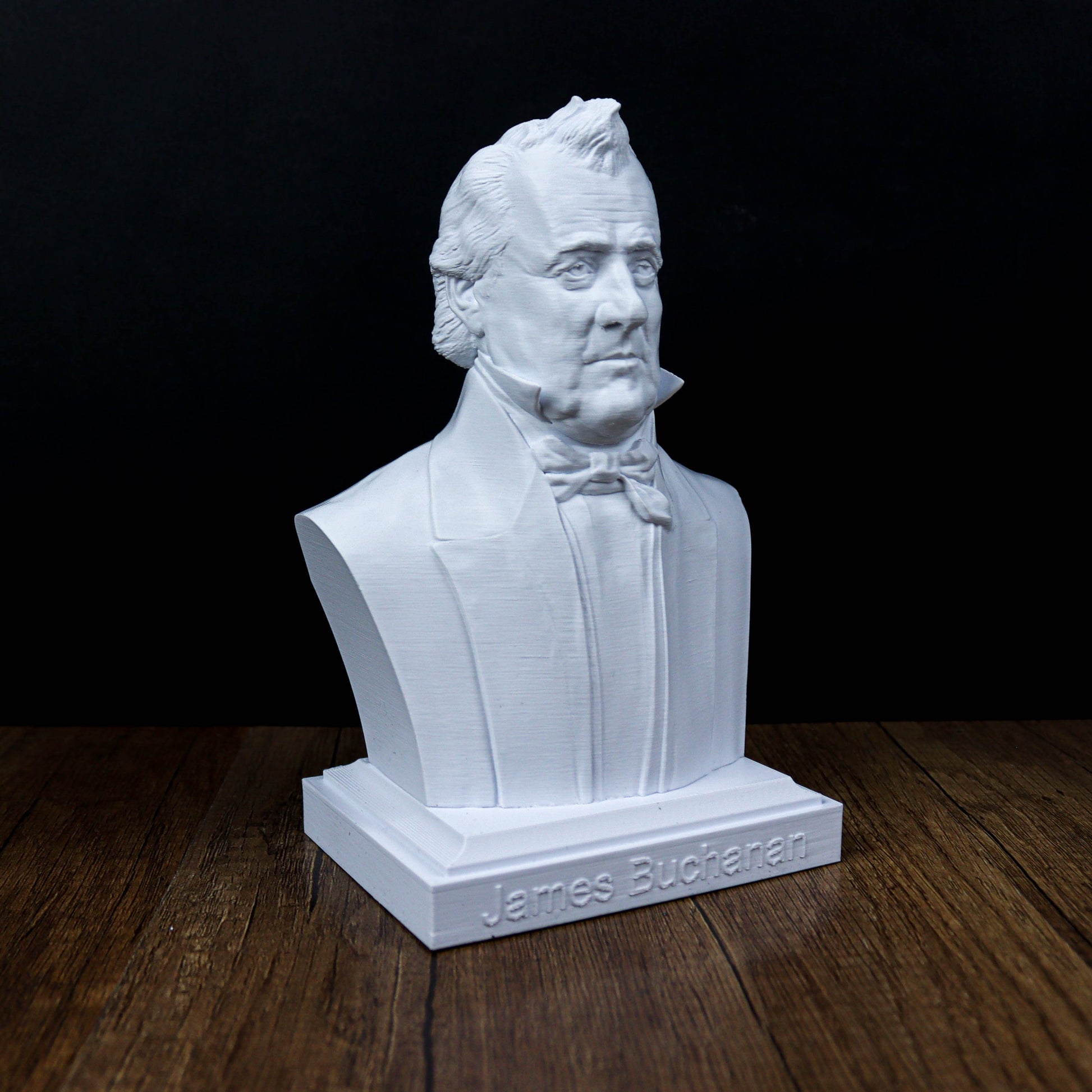 A white bust of a man wearing a suit and tie, sitting on a wooden surface.