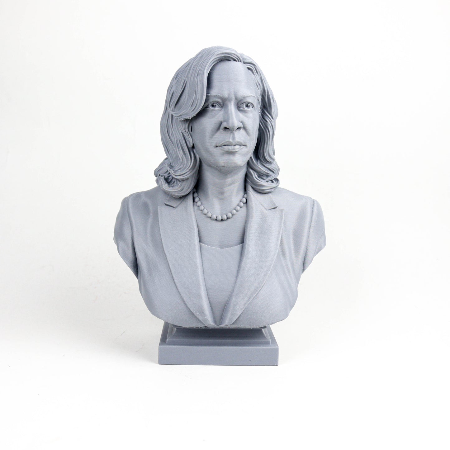 A gray bust sculpture of a woman with long hair and a pearl necklace, wearing a jacket.