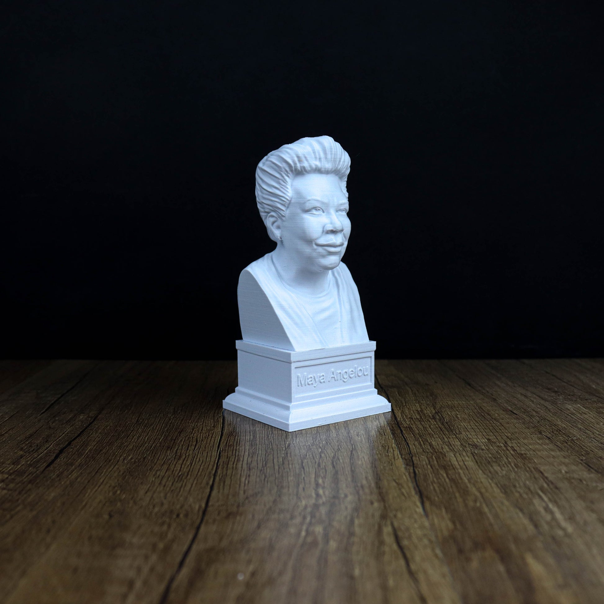 A white bust of a person is sitting on a wooden surface against a black background.