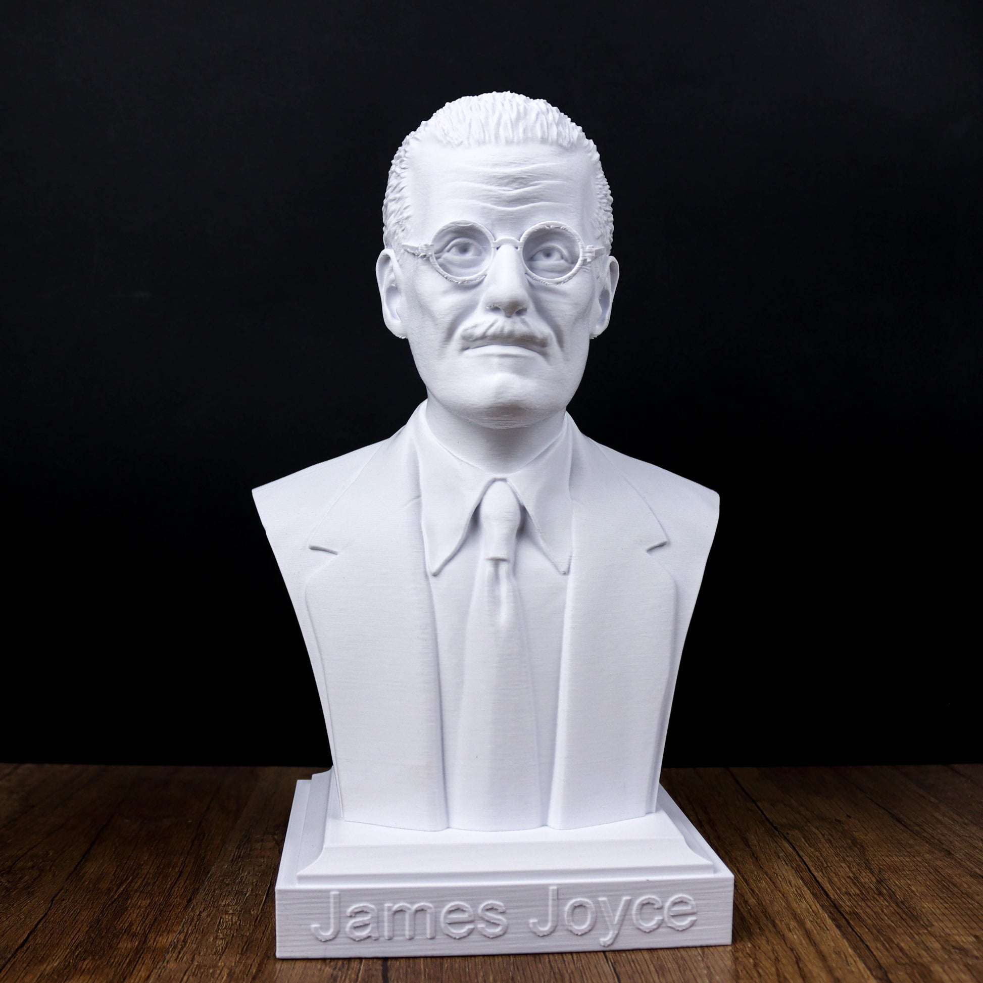 A white bust of a man wearing glasses and a suit, with the name "James Joyce" engraved on the base.