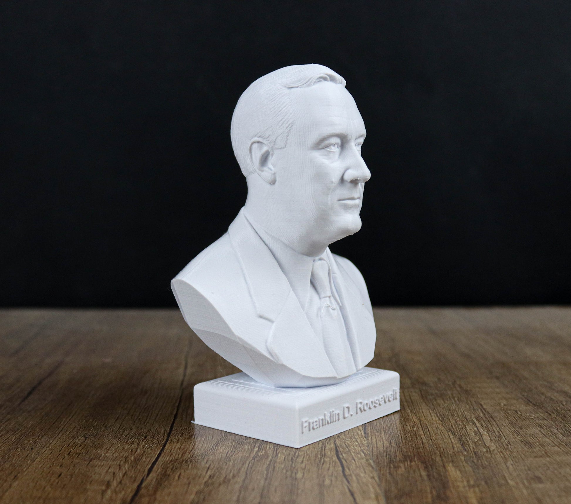 A white bust of a man, likely Franklin D. Roosevelt, is displayed on a wooden surface.