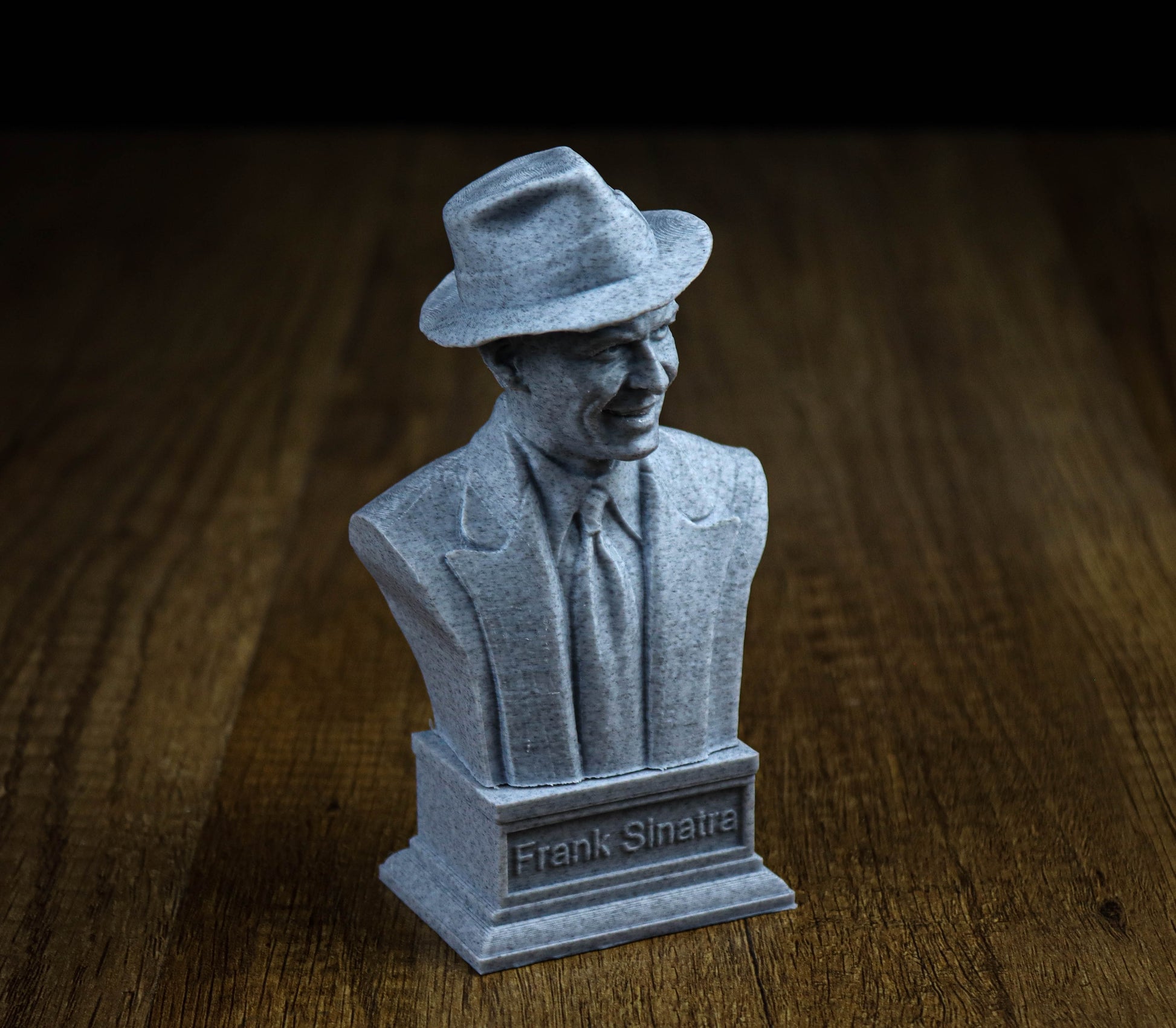 A bust of Frank Sinatra, a famous American singer and composer, is displayed on a wooden surface.