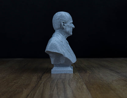 A gray bust of a man is displayed on a wooden surface against a dark background.