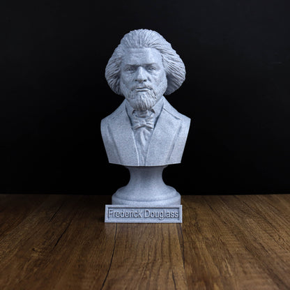 A bust of Frederick Douglass, a prominent African American author and abolitionist, is displayed on a wooden surface against a black background.