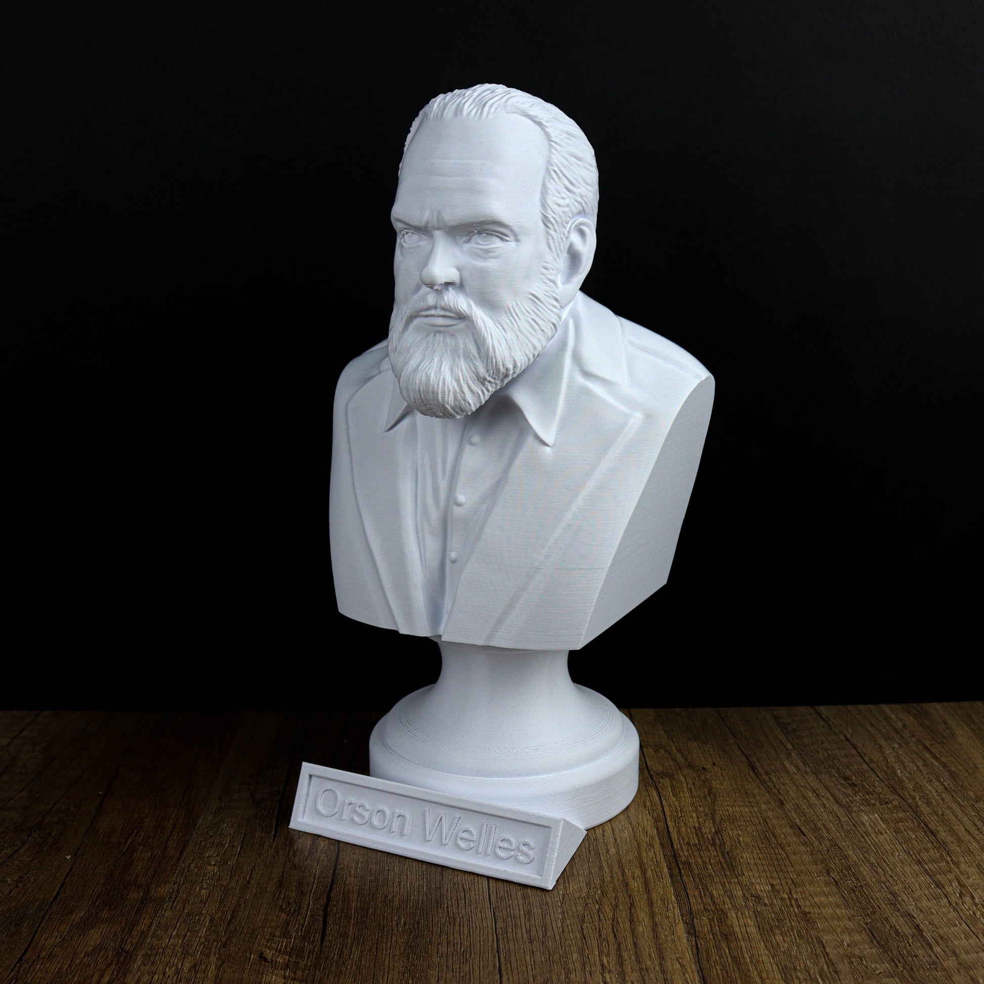 A white bust of a bearded man wearing a suit, placed on a wooden surface.