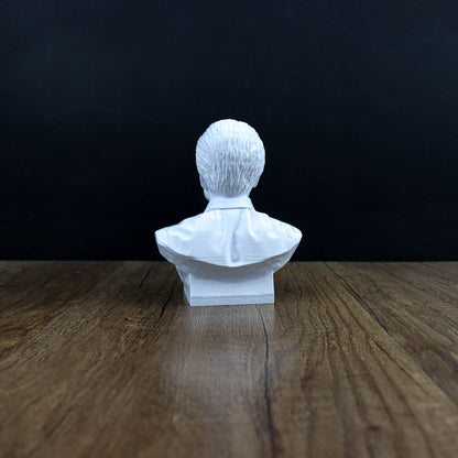 A white bust of a person sitting on a wooden surface against a dark background.