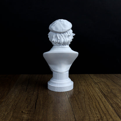 A white bust sculpture of a person's head is displayed on a wooden surface against a dark background.