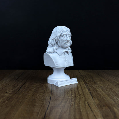 A white bust of a man with long hair and a mustache is displayed on a wooden surface against a black background.