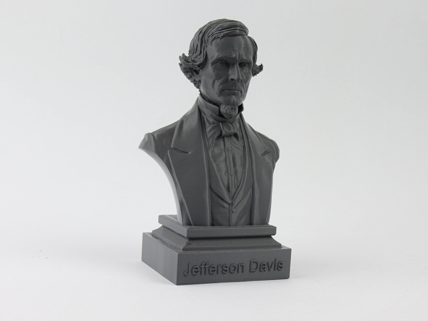 A black bust of a man, likely a historical figure, with a formal suit and tie.