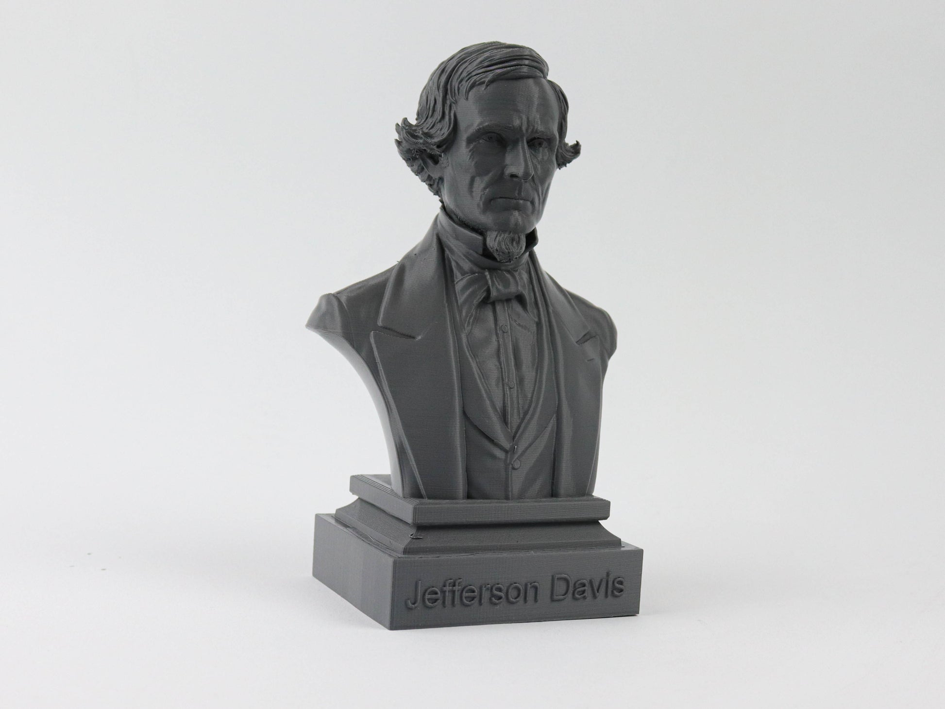 A black bust of a man, likely a historical figure, with a formal suit and tie.