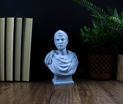 A gray bust of a man is displayed on a wooden surface, surrounded by books and a potted plant.