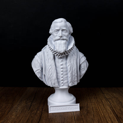 A white bust of a bearded man wearing a ruffled collar, standing on a wooden surface.