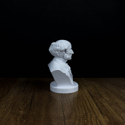 A white bust of a man is displayed on a wooden surface against a dark background.