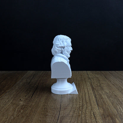 A white bust of a person is sitting on a wooden surface against a dark background.