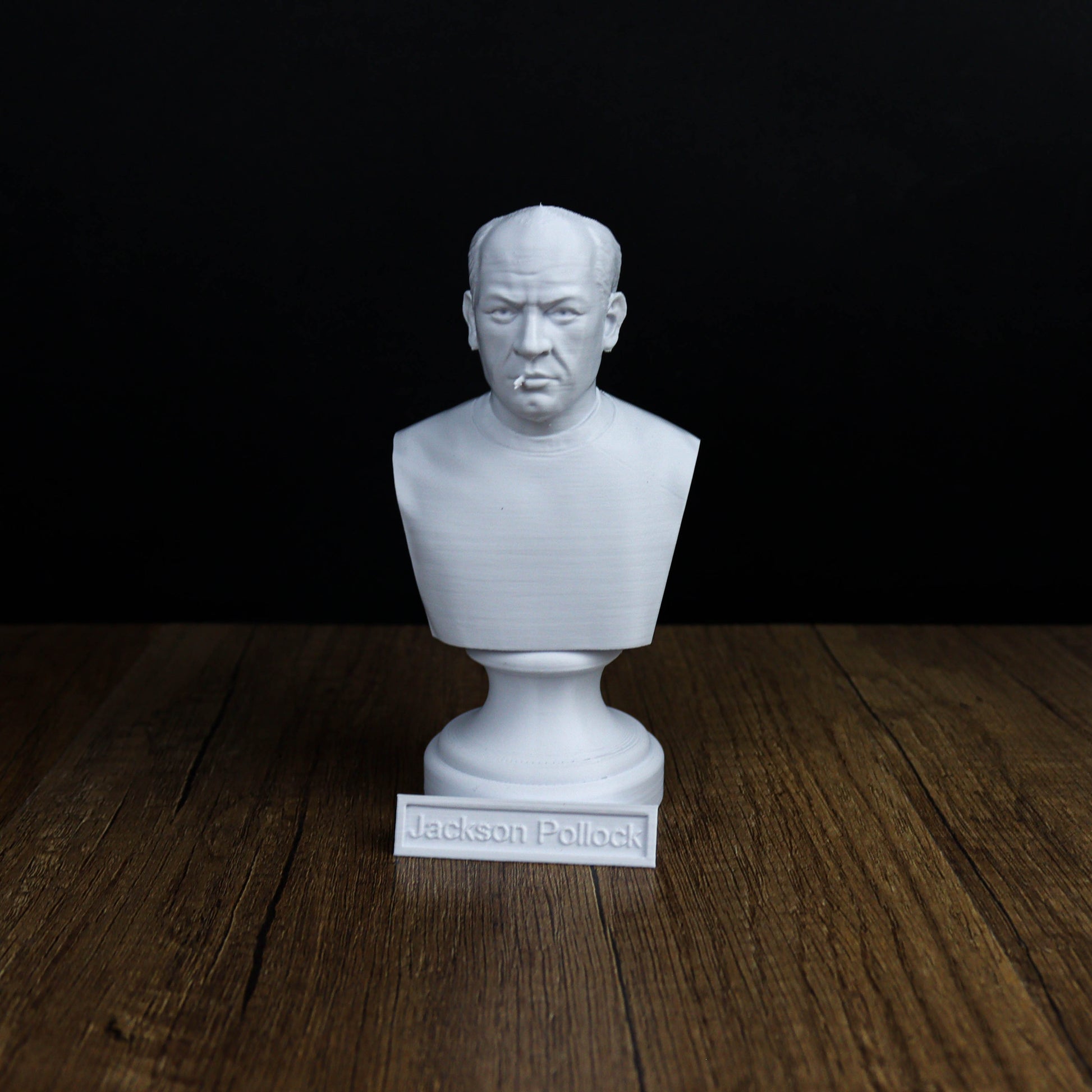 A white bust of a man is displayed on a wooden surface, with a nameplate below it.