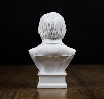 A white bust sculpture of a person's head is displayed on a wooden surface against a black background.