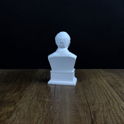 A white bust of a person sitting on a wooden surface against a dark background.