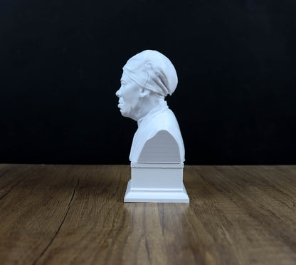 A white bust of a person is sitting on a wooden surface against a black background.