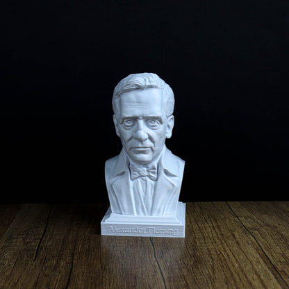 A white bust of a man wearing a suit and bow tie, placed on a wooden surface against a black background.