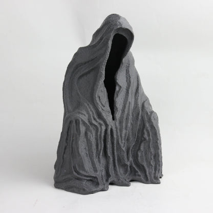 A dark, abstract sculpture with a hooded figure and a textured, organic shape.