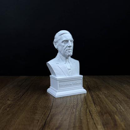 A white bust of a man is displayed on a wooden surface against a black background.