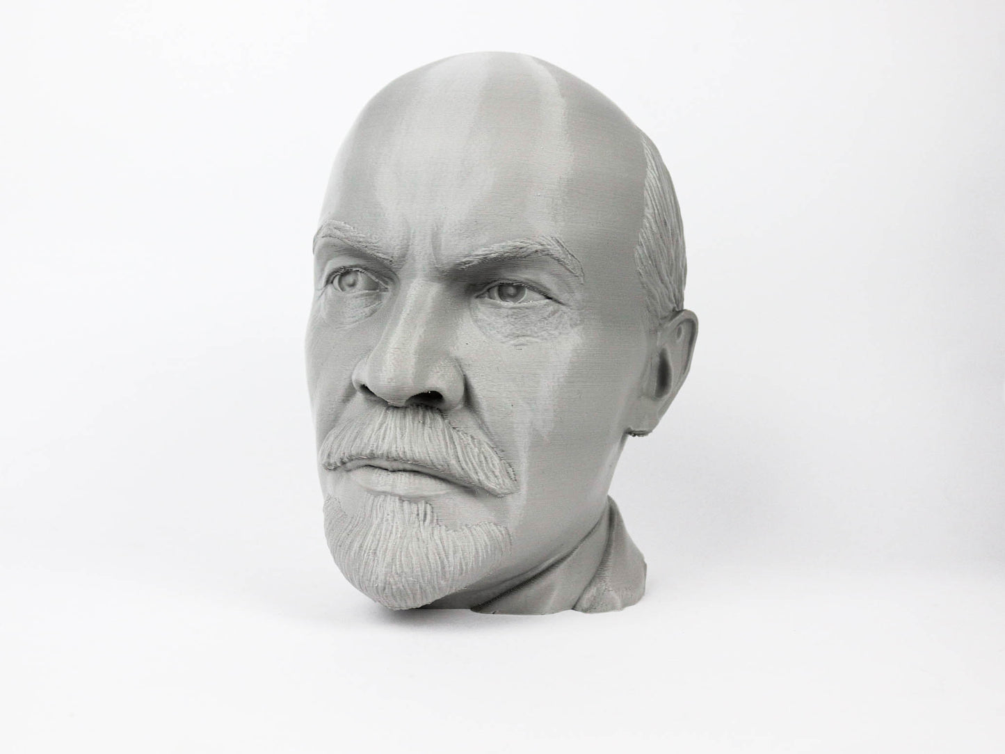 A black and white image of a man's head, possibly a bust, with a serious expression.