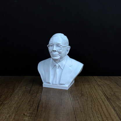 A white bust of a man wearing glasses and a suit is displayed on a wooden surface against a black background.