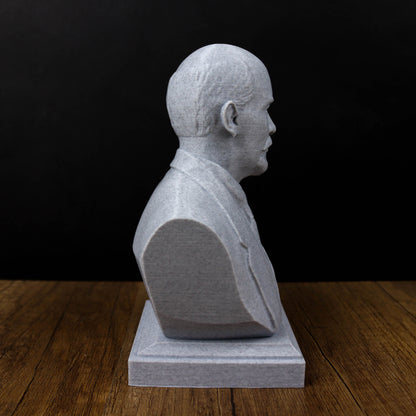 A white bust of a man is displayed on a wooden surface against a black background.