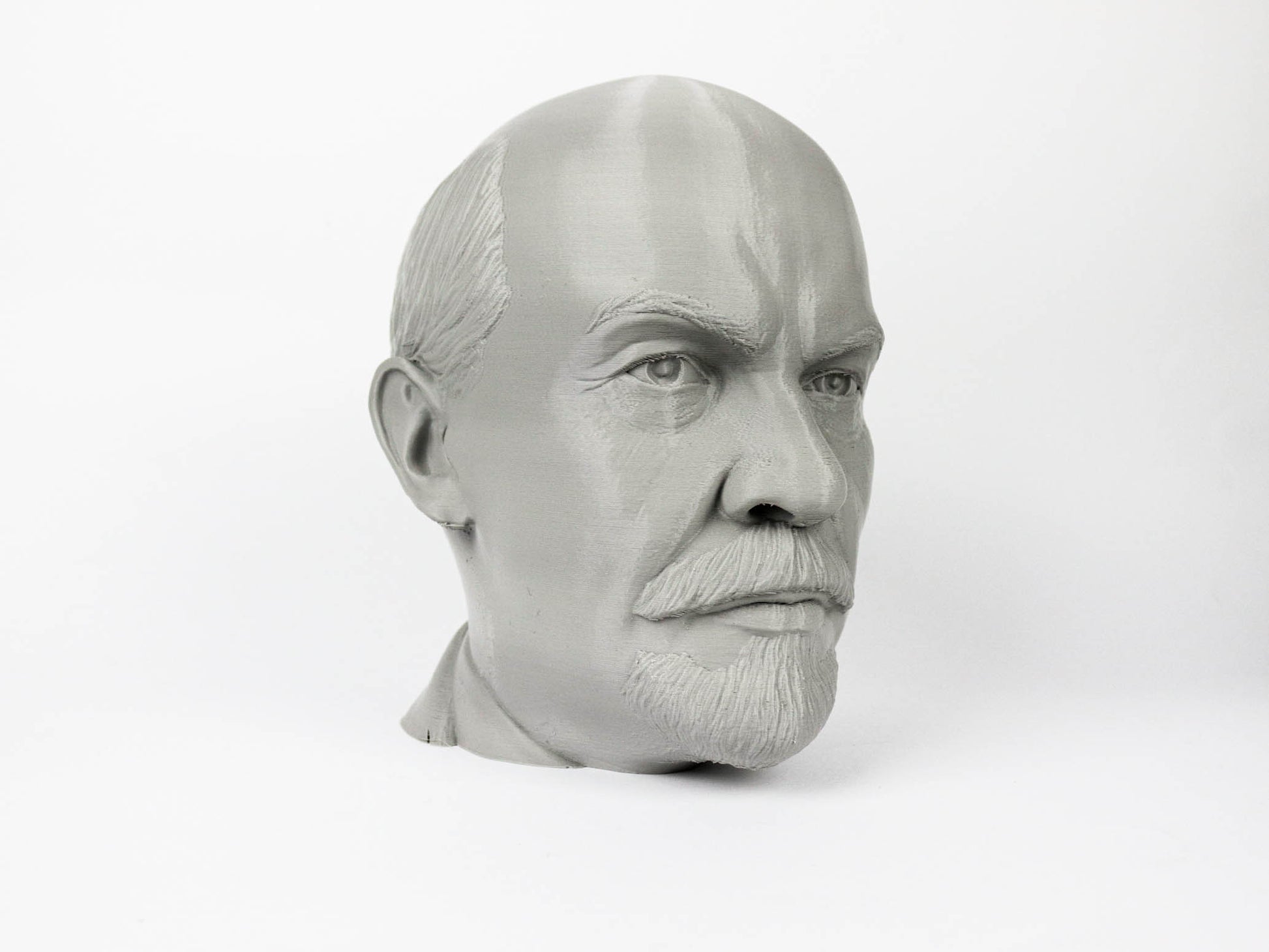 A gray bust of a man's head, with a serious expression, is shown against a plain white background.