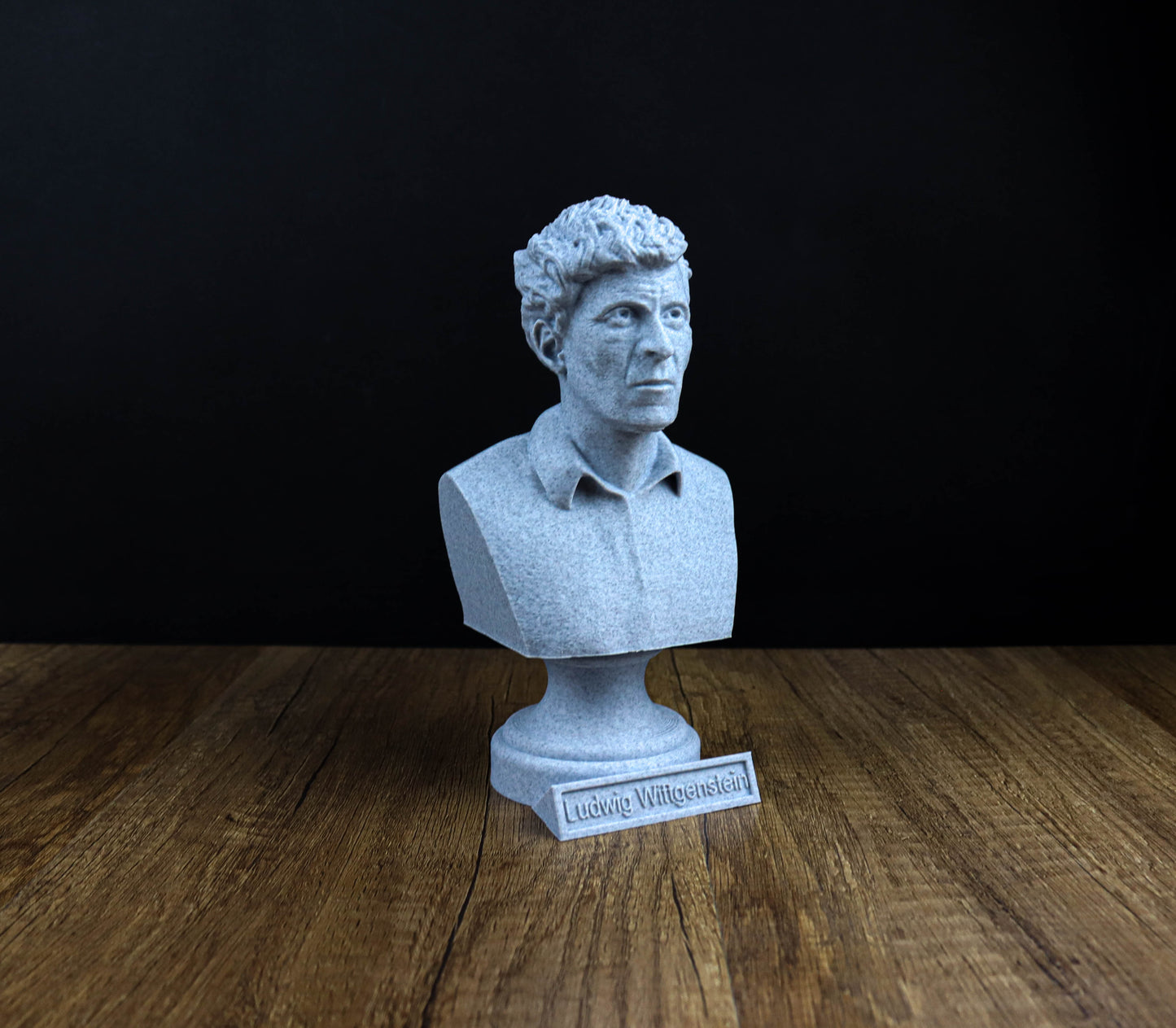 A white bust of a man is displayed on a wooden surface, with a small plaque in front of it.