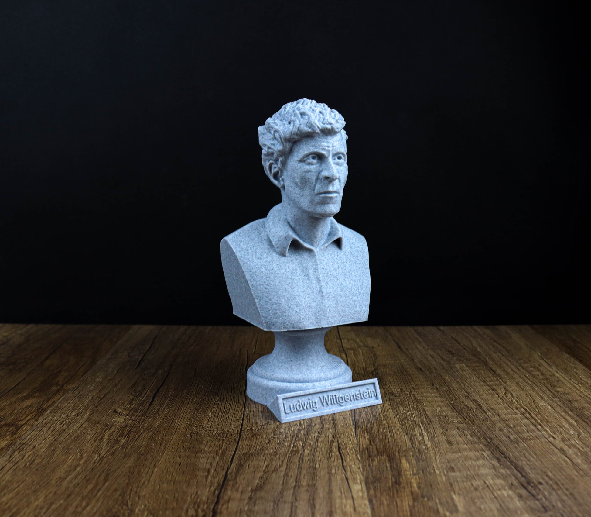 A white bust of a man is displayed on a wooden surface, with a small plaque in front of it.