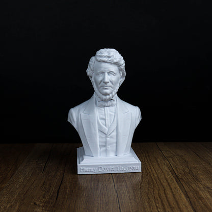 A white bust of a man wearing a suit and tie, standing on a wooden surface against a black background.