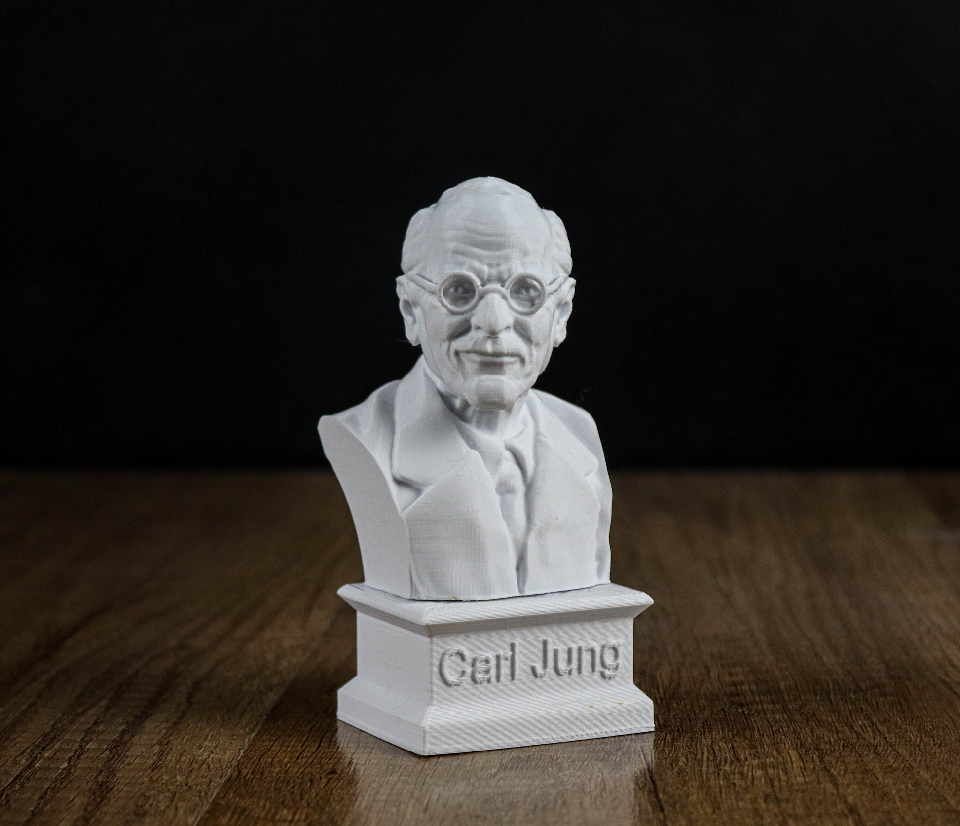A white bust of a man wearing glasses and a suit, sitting on a pedestal with the name "Carl Jung" engraved on it.