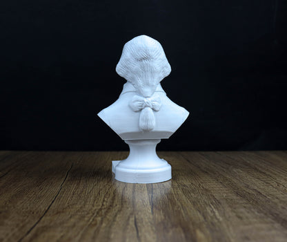 A white bust sculpture of a person is displayed on a wooden surface against a dark background.