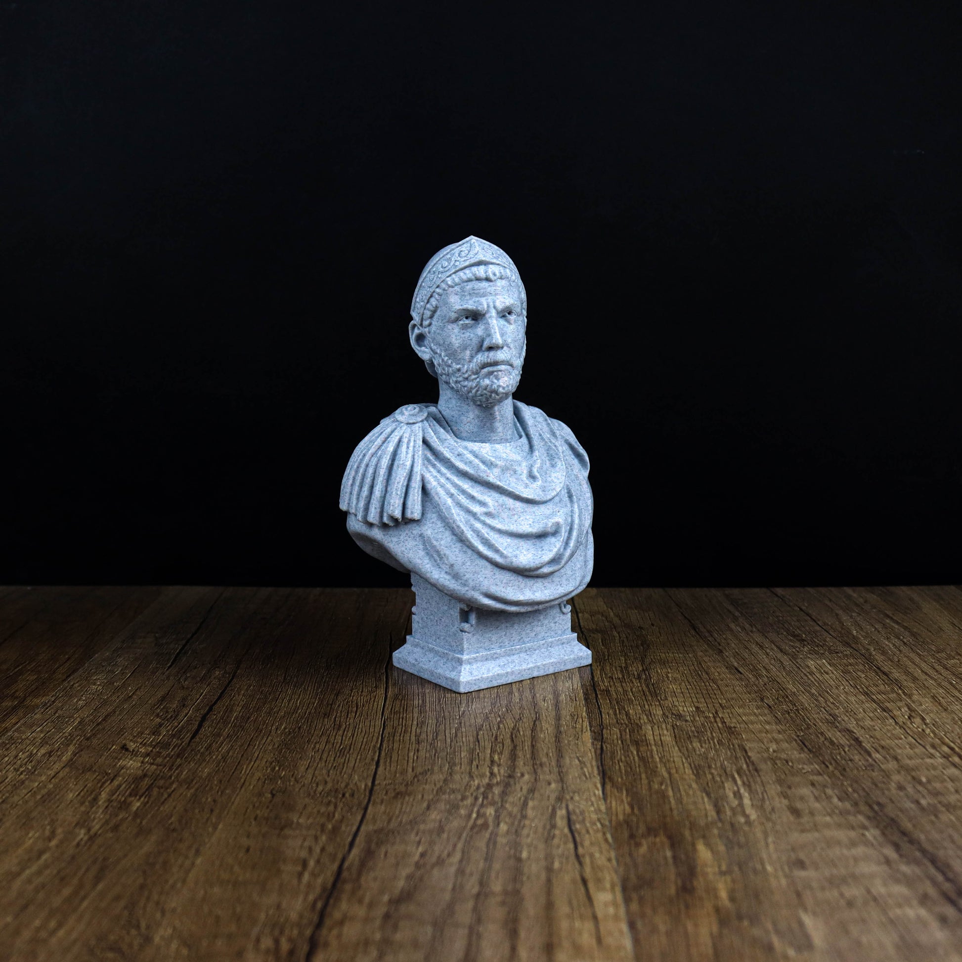 A white bust of a man is displayed on a wooden surface against a black background.