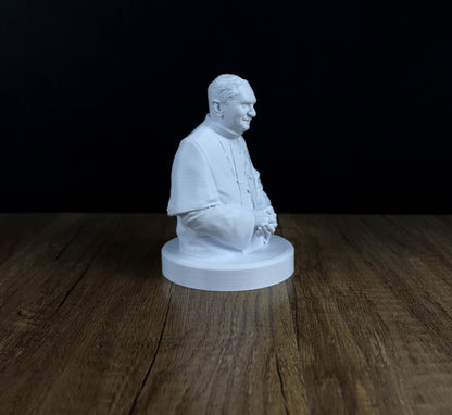 A white 3D printed statue of a man in a robe, sitting on a wooden surface.